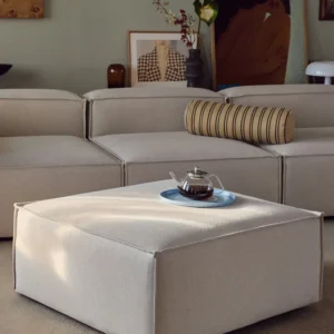 The LENNON ottoman with a wooden top can be used either as a coffee table or as a connecting element for the sofa—for a stylish look, storage, and practical use