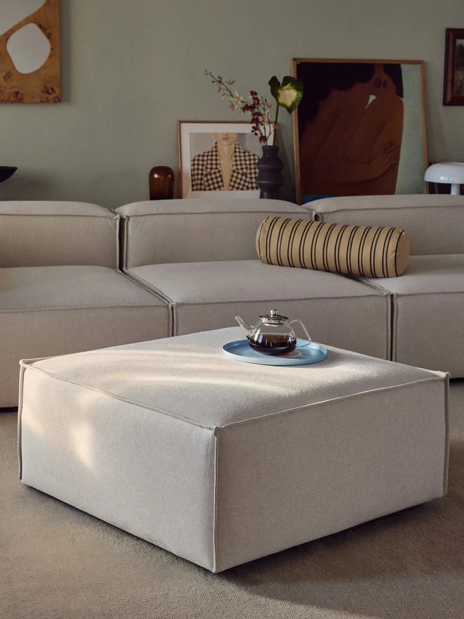 The LENNON ottoman with a wooden top can be used either as a coffee table or as a connecting element for the sofa—for a stylish look, storage, and practical use
