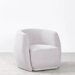 Nimbo armchair with curved compact design, upholstered in soft bouclé fabric, offering comfort and sophistication for versatile interiors