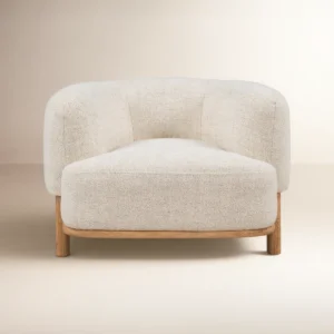 Cream upholstered barrel chair with wide seat, curved back, and natural wood legs in a modern living room setting.
