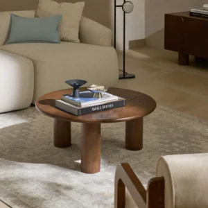 Didi round coffee table in solid oak wood with organic round shape and wide legs, available in natural, dark brown, or black finishes.