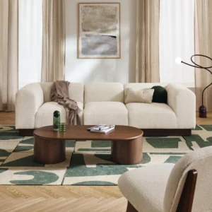 NATALIE modular sofa with rounded design, wooden base, and soft fabric cushions arranged in a contemporary living room.