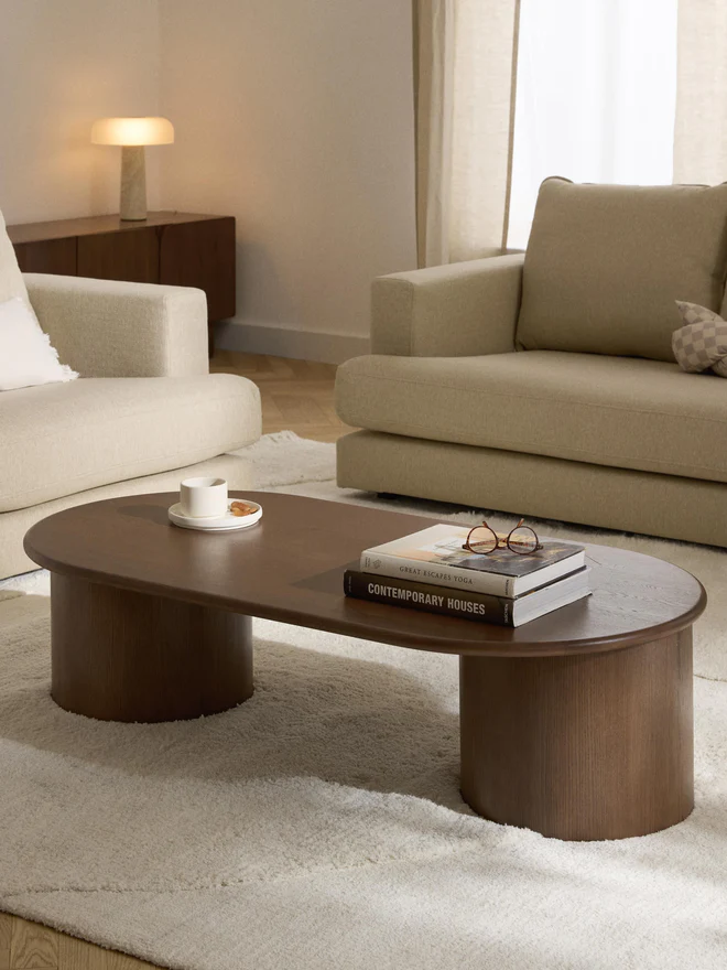 Oval Didi coffee table in solid oak wood with organic oval shape and wide round legs, available in natural, dark brown, or black finishes