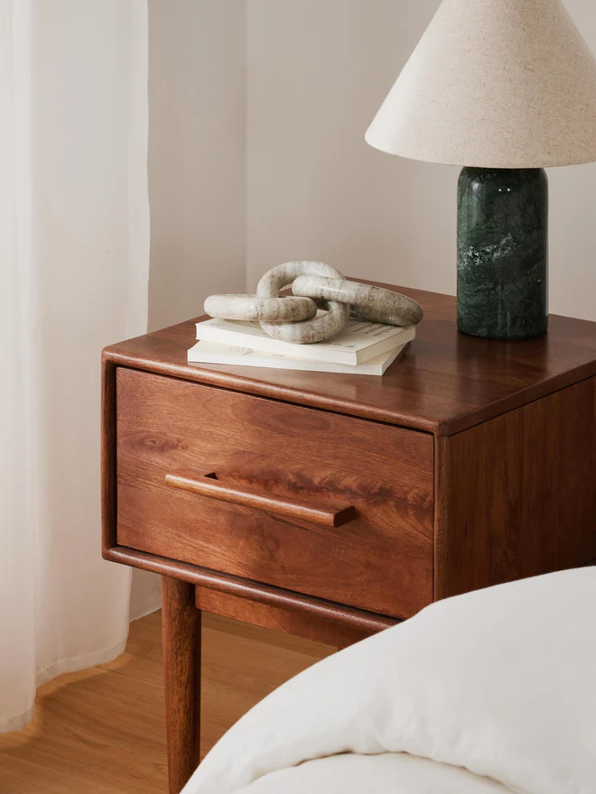 Paul bedside table made of mango wood with dark finish, tapered legs, and one drawer featuring a soft-close mechanism