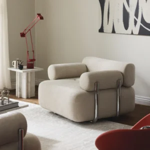 STELLA armchair in modern design with elegant lines, upholstered in high-quality fabric, paired with matching footstool for ultimate comfort.