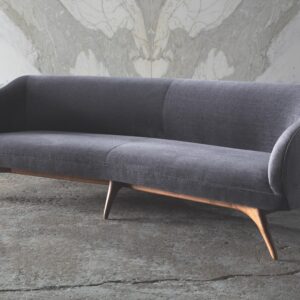 Fifth Avenue Wide Angle Sofa with soft V-shaped design, rounded arms, and tapered sculpted base in a contemporary living room.