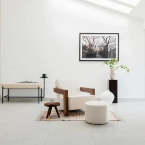 Modern upholstered lounge chair featuring a sculptural two-legged base, generously cushioned seat, and sleek architectural lines, ideal for a reading nook or living room corner